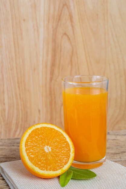 Glass of orange juice placed on wood.