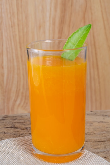 Glass of orange juice placed on wood.