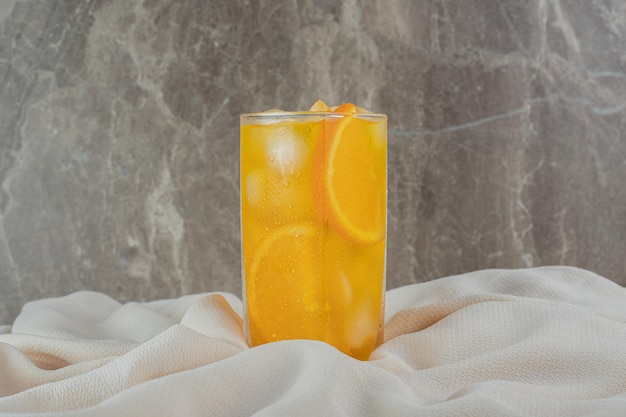 새틴 천에 얼음 조각이 든 오렌지 주스 한잔