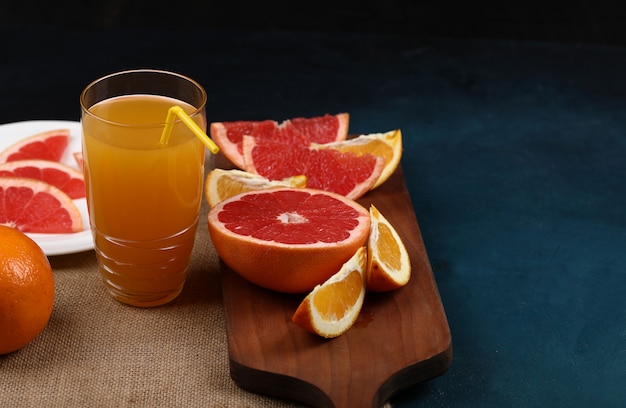 A glass of orange juice with sliced fruits.