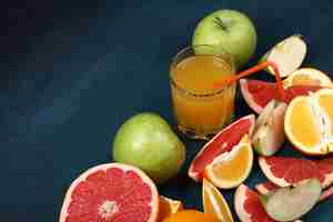 Free photo a glass of orange juice with sliced tropical fruits.