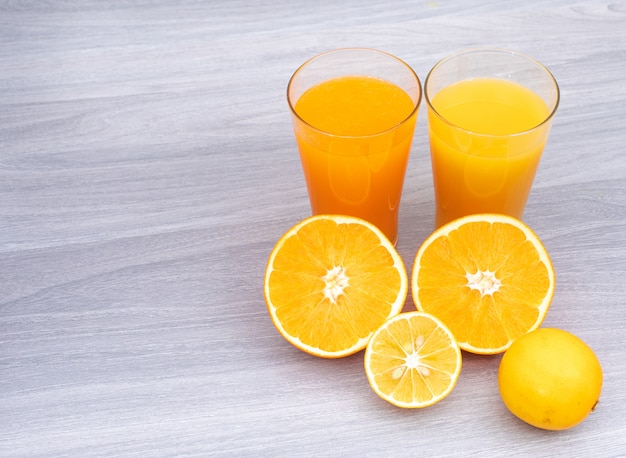 Free photo glass of orange and lemon juice on white wooden table