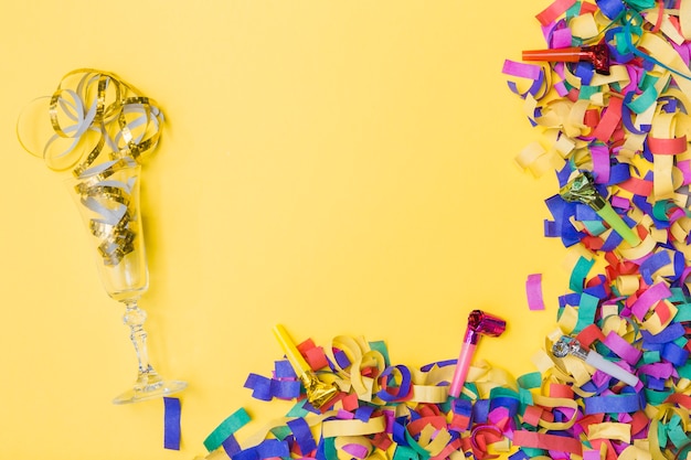 Glass and party horns near confetti