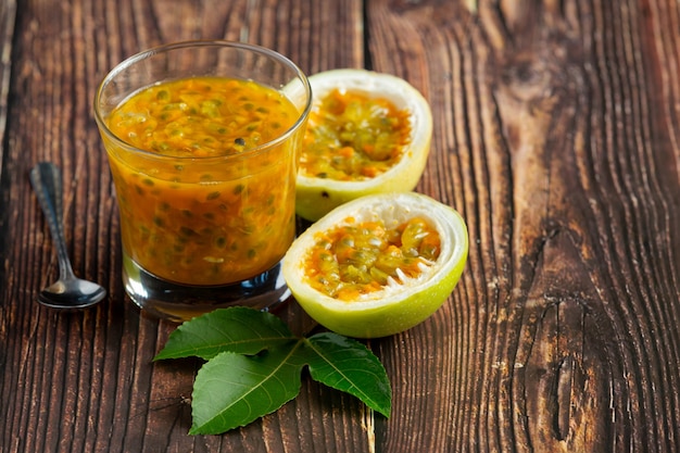 a glass of passion fruit juice and fresh passion fruit cut in half place on wooden  floor