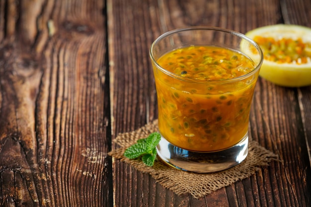 a glass of passion fruit juice and fresh passion fruit cut in half place on wooden  floor