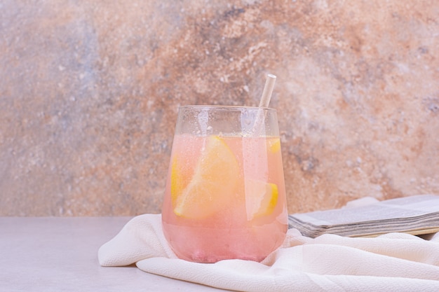 A glass of pink cocktail with lemon slices.