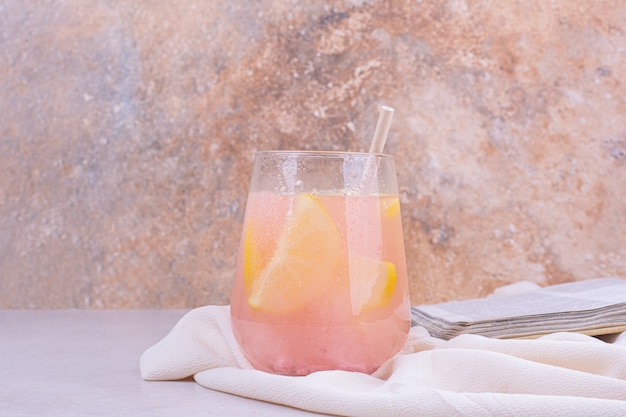 Стакан розового коктейля с дольками лимона.