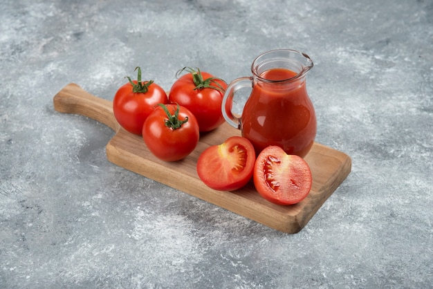 A glass pitcher of juice with fresh tomatoes.
