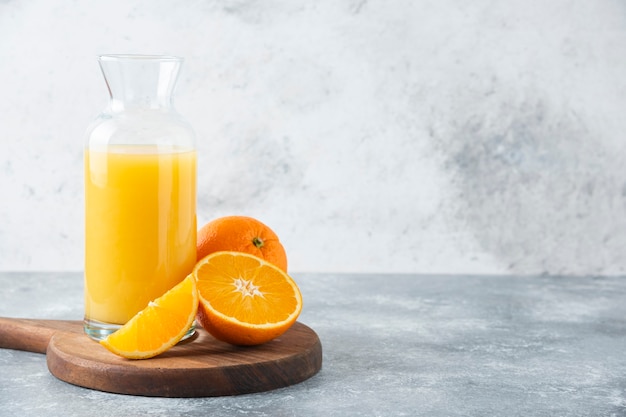 Glass pitcher of juice with slice of orange fruit .