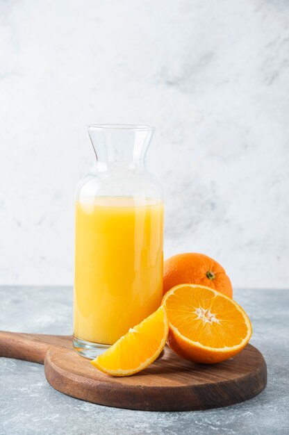 Glass pitcher of juice with slice of orange fruit .