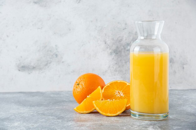 Glass pitcher of juice with slice of orange fruit .