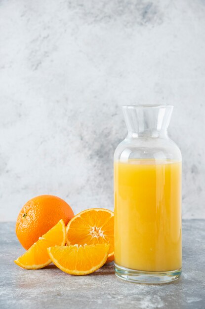 Glass pitcher of juice with slice of orange fruit .