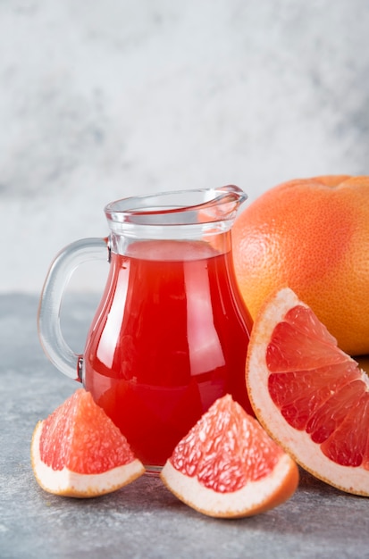 Бесплатное фото Стеклянный кувшин свежего грейпфрутового сока с кусочками фруктов.
