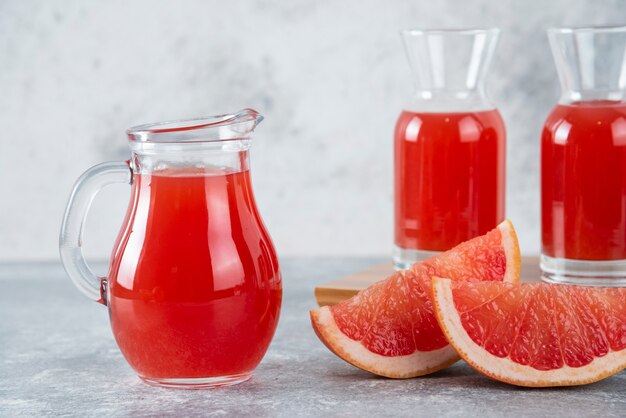 Glass pitchers of fresh grapefruit juice with slices of fruits . 