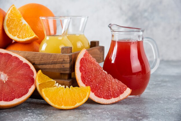 Glass pitchers of grapefruit juice with slices of orange fruits. 