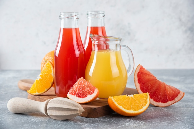 Glass pitchers of grapefruit juice with slices of orange fruits. 