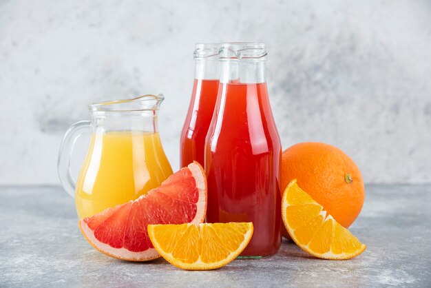 Glass pitchers of grapefruit juice with slices of orange fruits. 