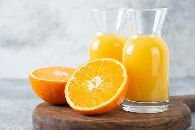 Glass pitchers of juice with slice of orange fruit .