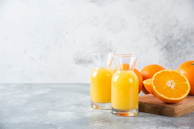 Glass pitchers of juice with slice of orange fruit .