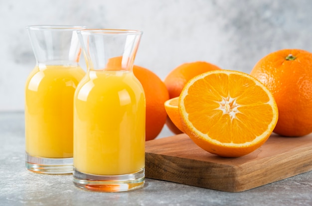 Glass pitchers of juice with slice of orange fruit .