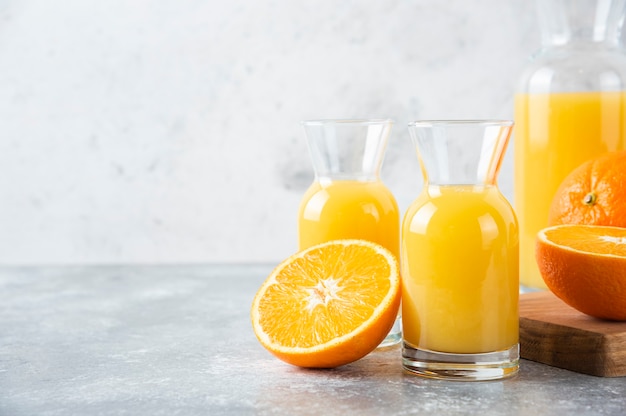 Glass pitchers of juice with slice of orange fruit .