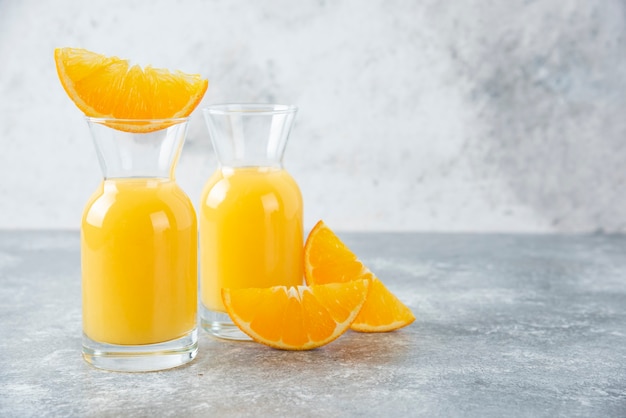 Glass pitchers of juice with slice of orange fruit .