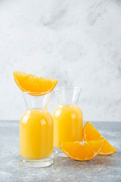 Glass pitchers of juice with slice of orange fruit .