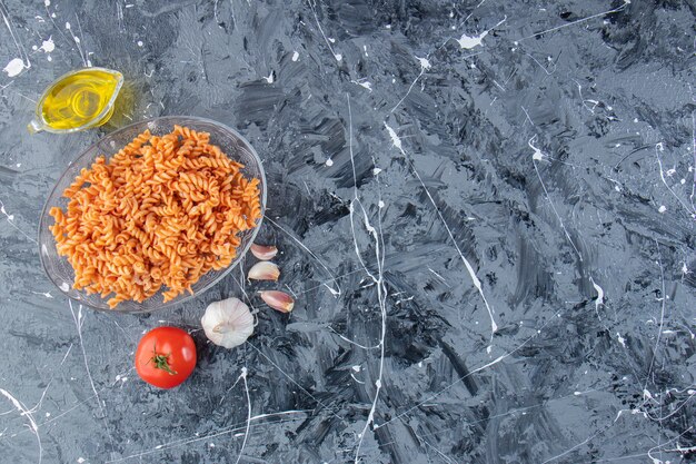 Стеклянная тарелка вкусной пасты фузилли и овощей на мраморном фоне.