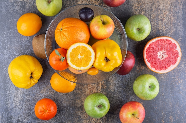 Glass plate of fresh fruits on top of many fruits.