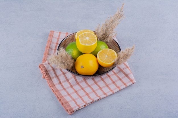 Стеклянная тарелка свежих сочных лимонов на камне.