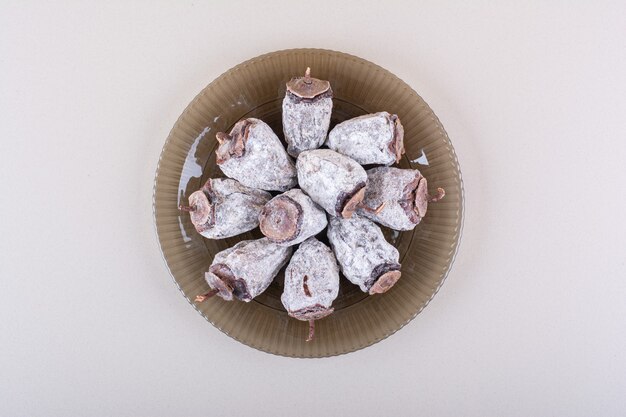 Glass plate full of dried persimmons on white background. High quality photo