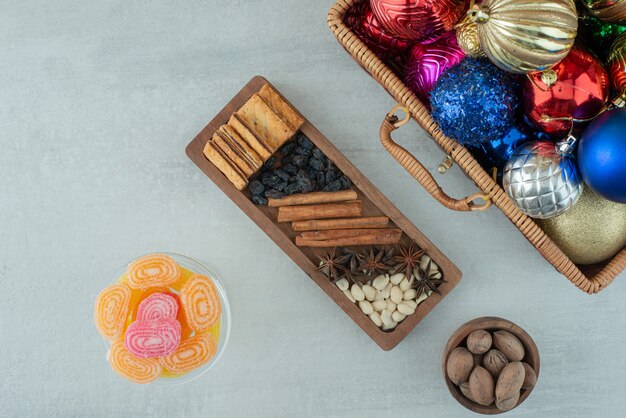 Free photo a glass plate full of sugar marmalade and christmas festive balls on marble background. high quality photo