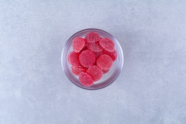 A glass plate full of sugary jelly candies on gray surface 