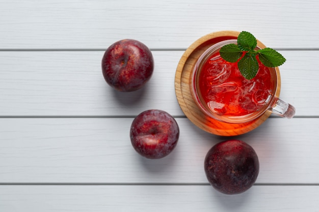 glass of plum put on white wooden floor