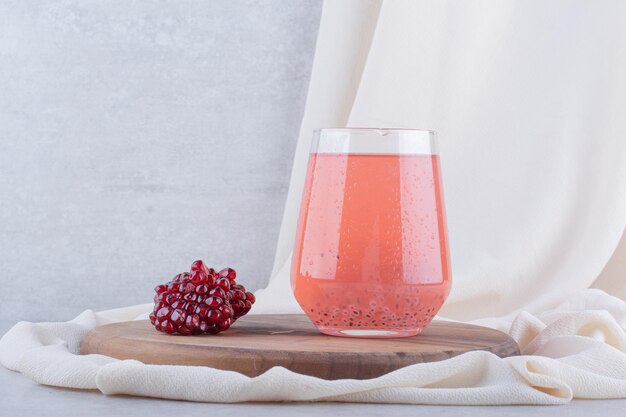 A glass of pomegranate juice on wooden board with seeds. High quality photo