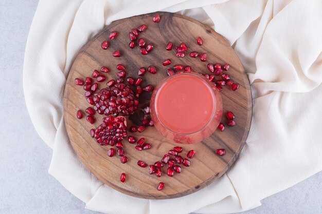 A glass of pomegranate juice on wooden board with seeds. High quality photo