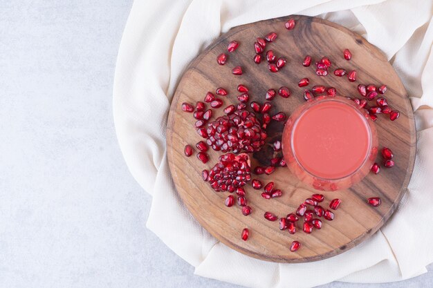 A glass of pomegranate juice on wooden board with seeds. High quality photo