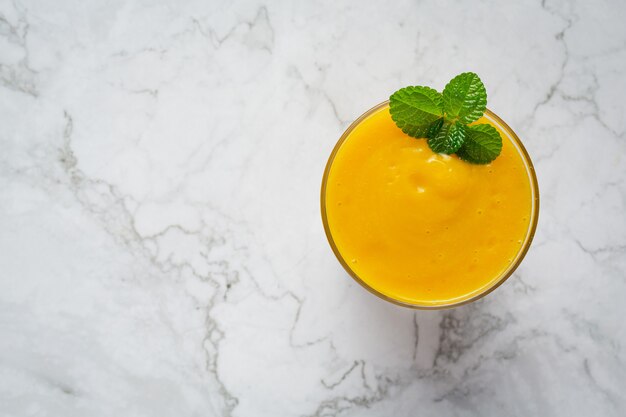 a glass of pumpkin juice place on white marble  floor