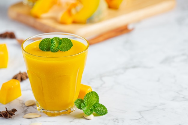 a glass of pumpkin juice place on white marble  floor