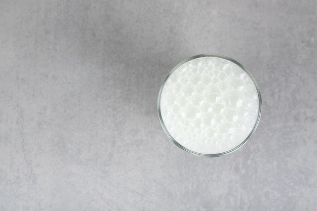 A glass of pure cold water with bubbles on gray surface