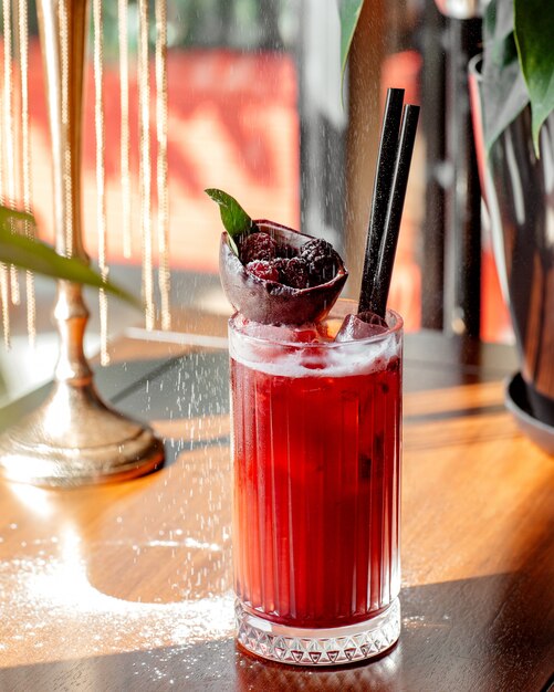 A glass of raspberry cocktail garnished with chocolate bowl with raspberries