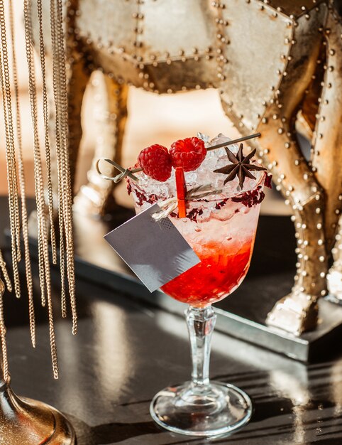 A glass of raspberry cocktail with ice