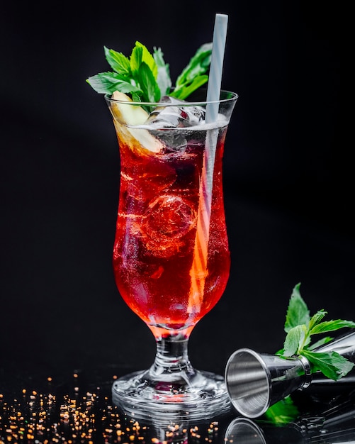 Free photo a glass of red drink with mint leaves and pipe.