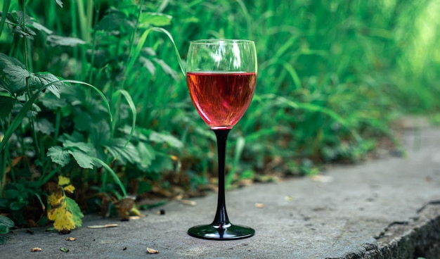 ぼやけた草の背景に赤ワインのグラス