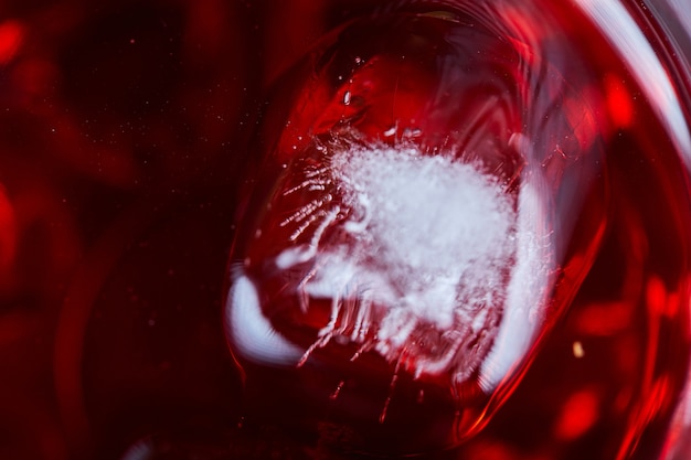 A glass of red wine with ice on table, close up