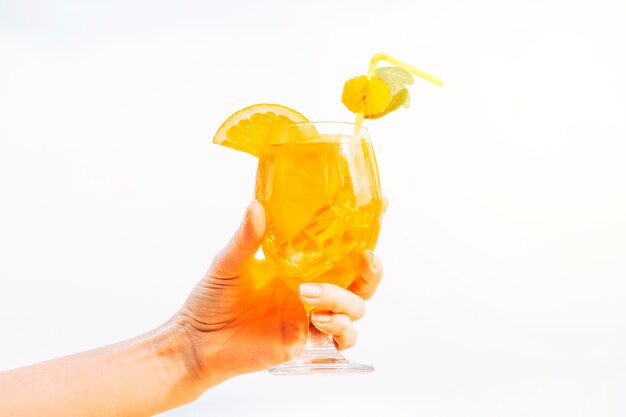 Glass of refreshing orange drink in hand