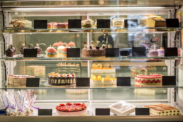 Glass showcase of pastry shop with variety of fresh cakes and pastries. Popular sweet desserts offered for sale