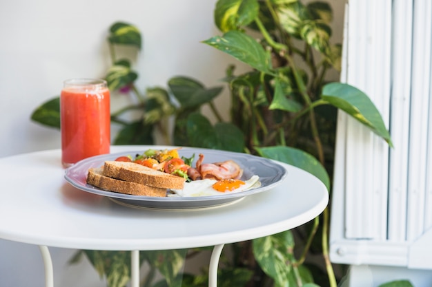 Glass of smoothie; breakfast on plate over the white round table