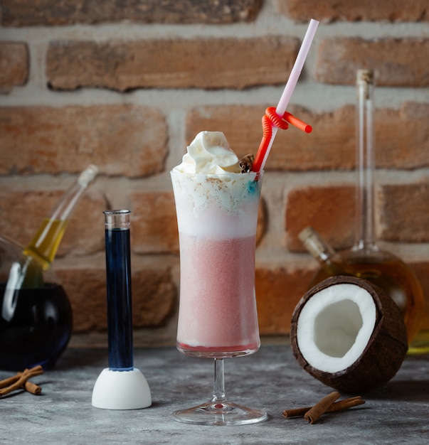 A glass of smoothy with whipping cream in the top and chopstick.