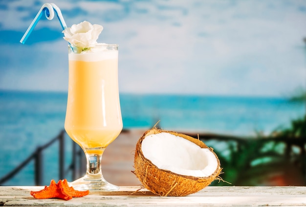 Стакан безалкогольного желтого напитка оранжевая морская звезда и треснутый кокос